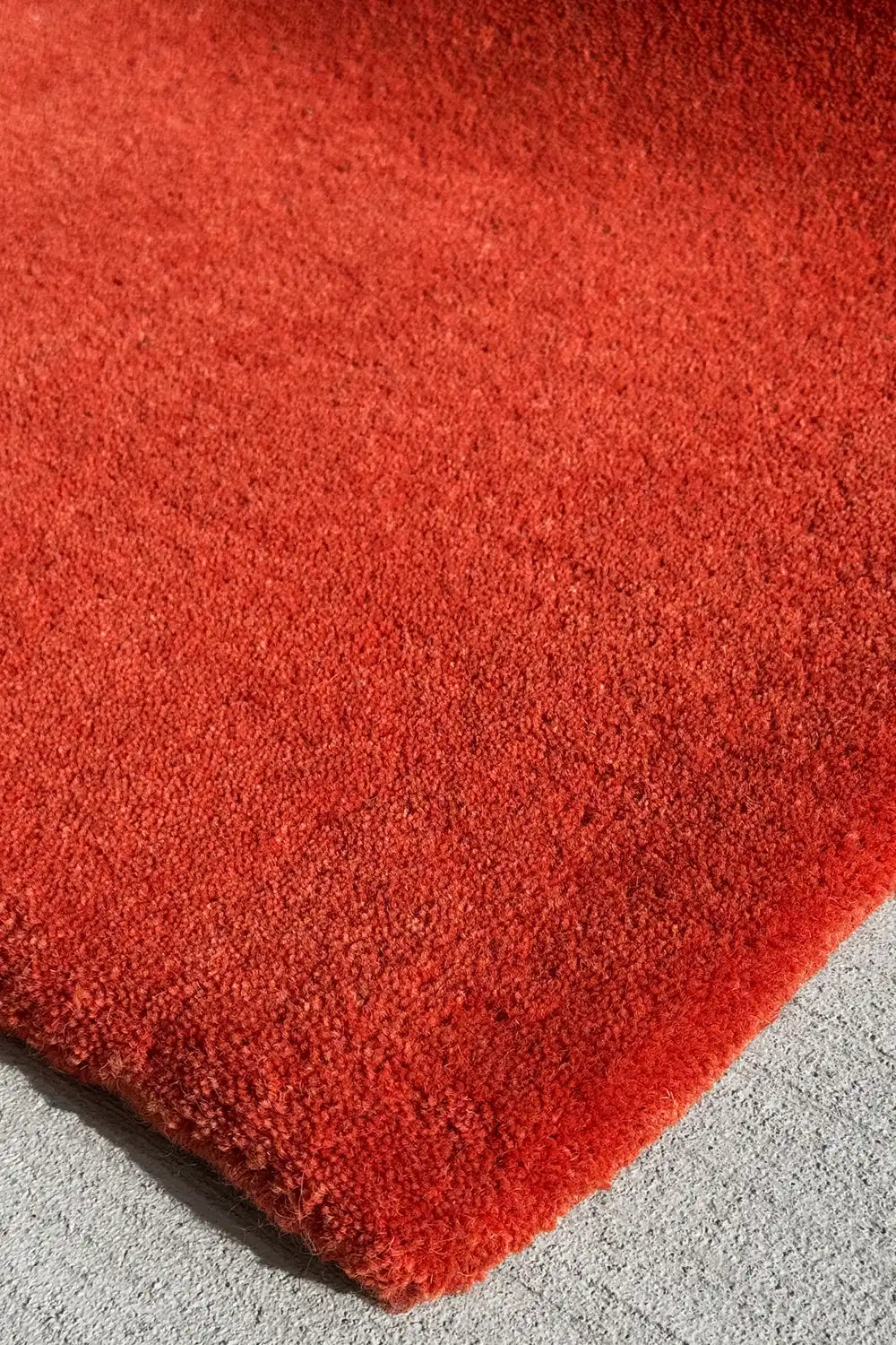 Close-up of a burnt orange rug on a gray surface