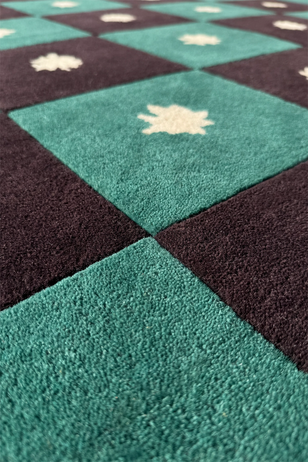 Close-up of a checkered pattern rug with alternating black and teal green squares texture
