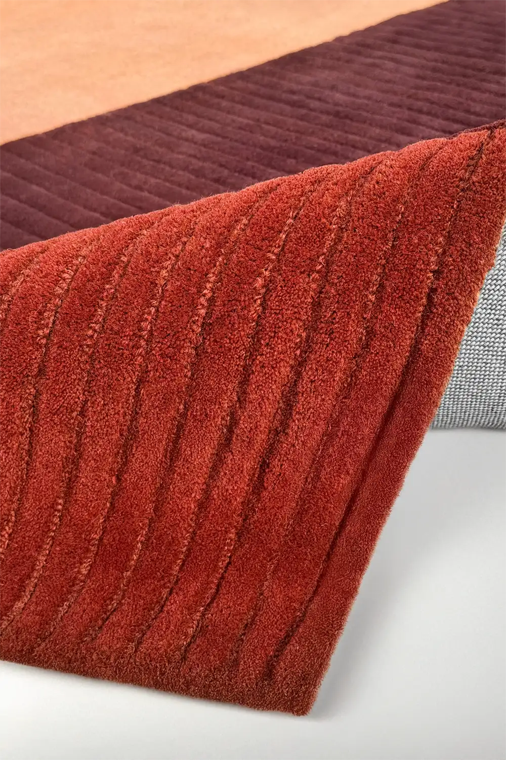 Close-up of a textured red rug with a neutral background