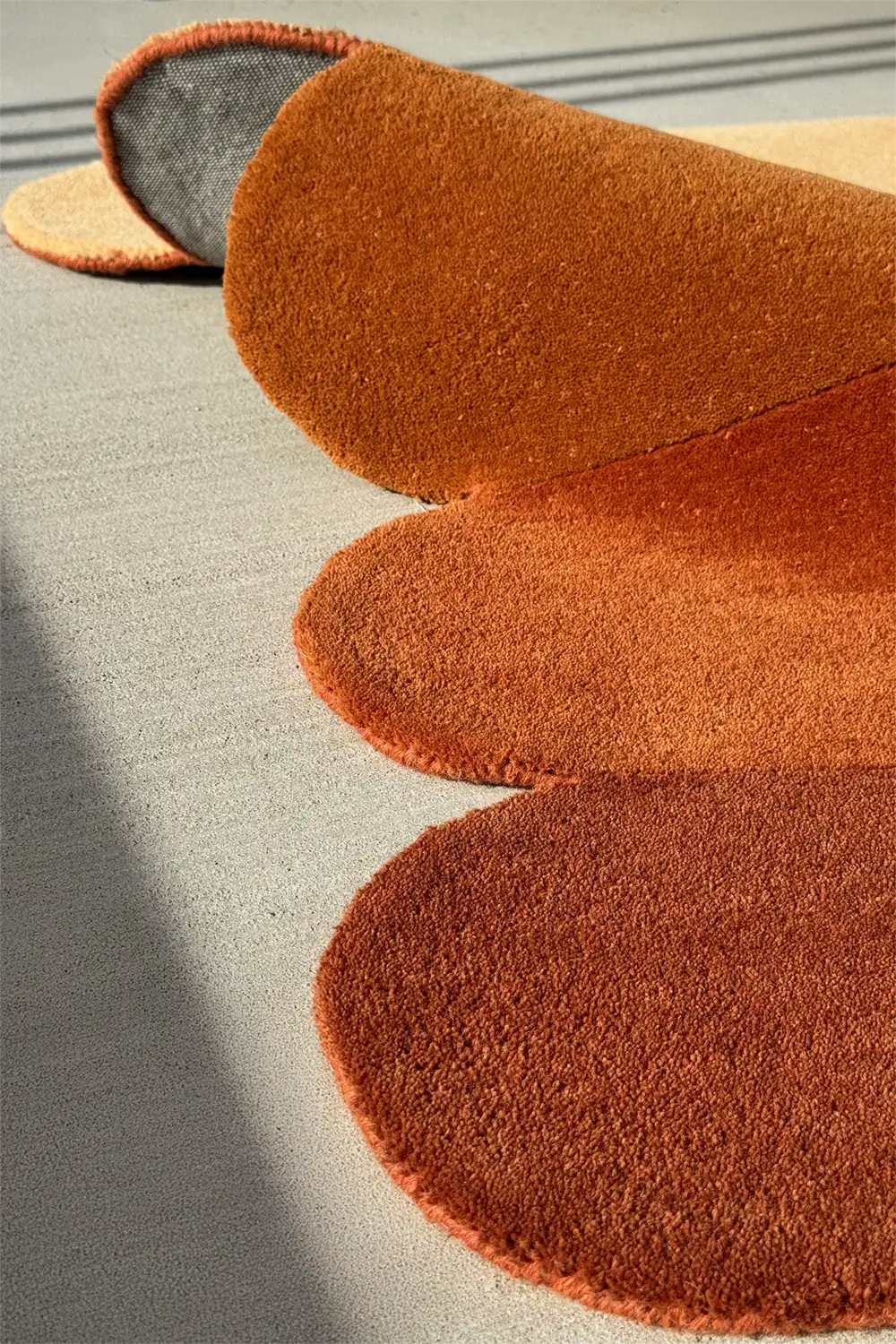 Burnt orange and tan rug with layered curved silhouette, perfect for warm, neutral living rooms