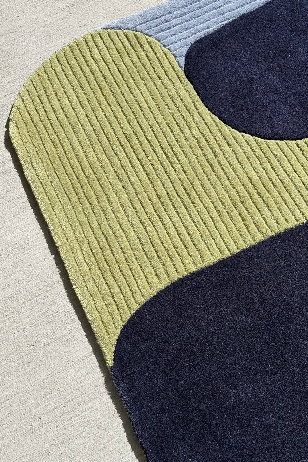 Irregular shape funky rug with rounded edge and tubular abstract forms in navy and green