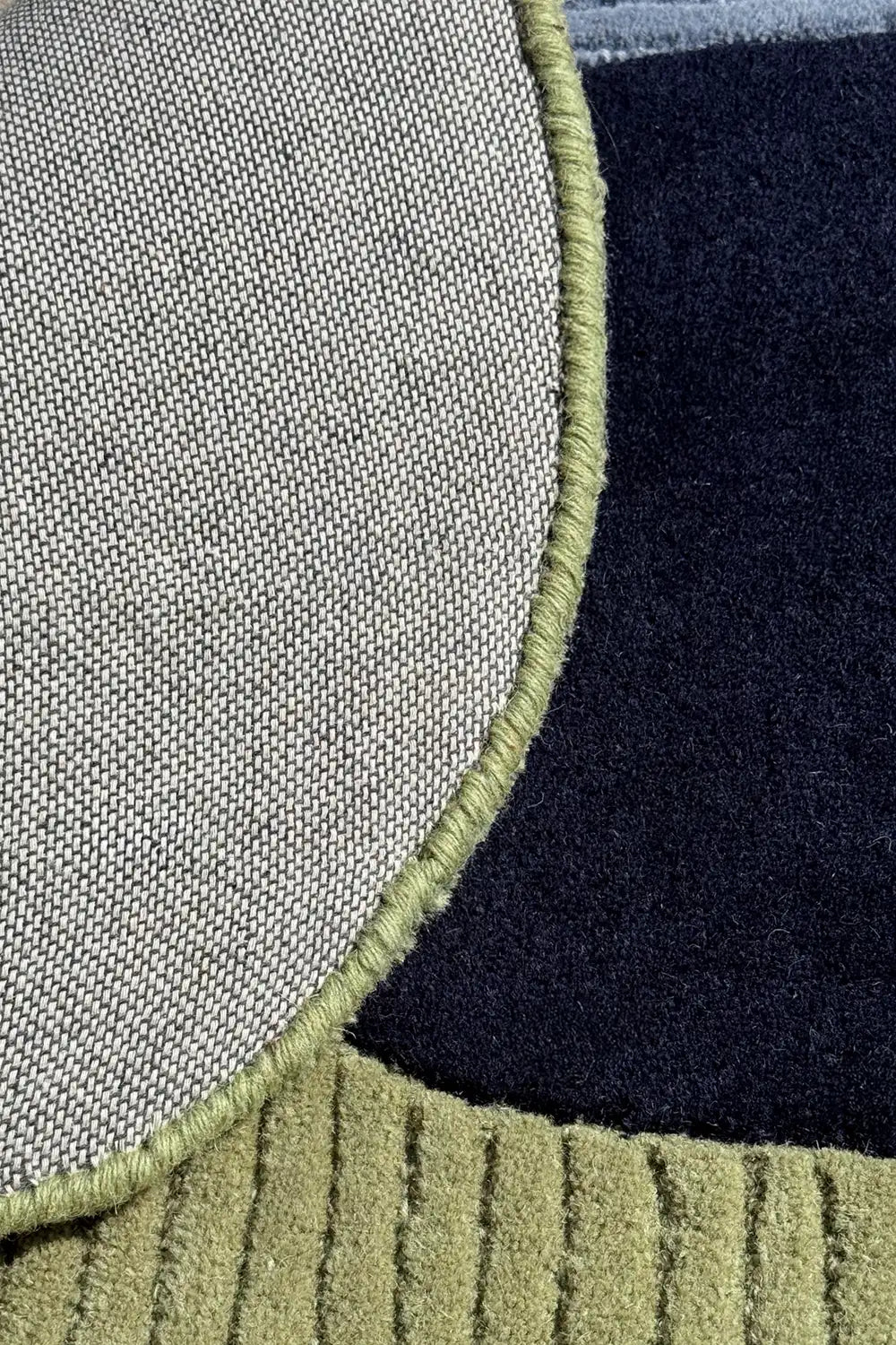 Tufted wool area rug with bold color blocks in navy and green, bound in soft sculptural curves