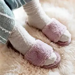 Pink slippers worn with white socks on a soft shaggy wool rug