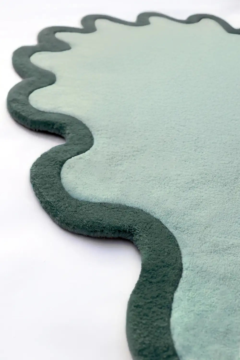 Detail of hand-tufted sage forest green and emerald wool rug with sculpted waves