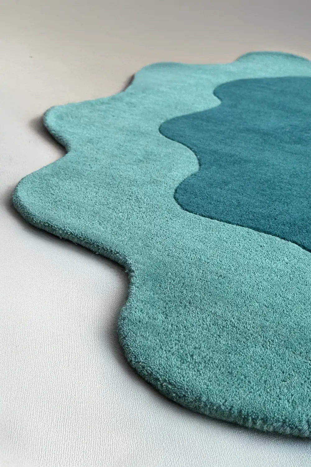 Wavy edge detail of teal novelty rug with puddle-like outline, perfect as a unique shaped rug or scalloped area rug for kids’ rooms