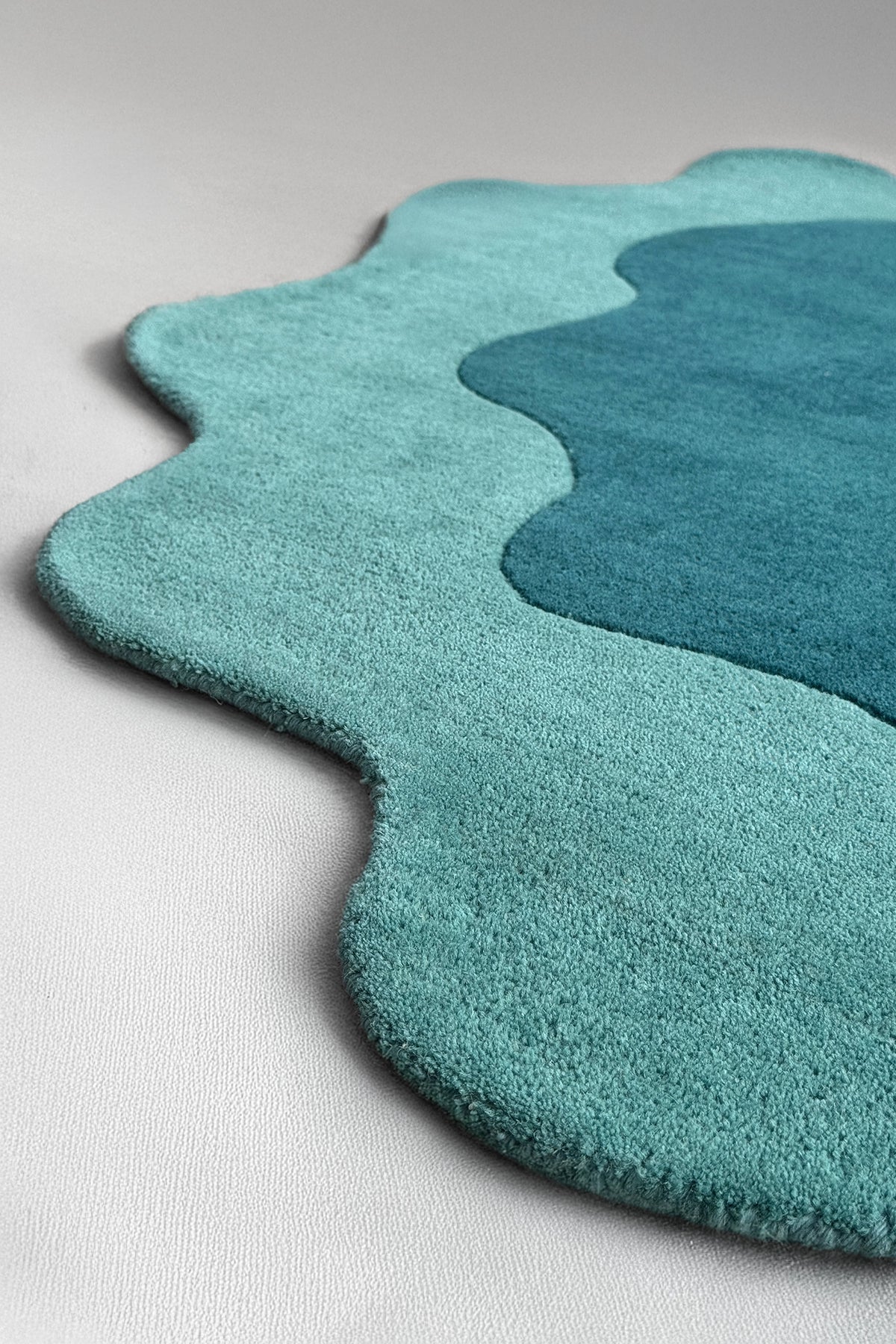 Wavy edge detail of teal novelty rug with puddle-like outline, perfect as a unique shaped rug or scalloped area rug for kids’ rooms