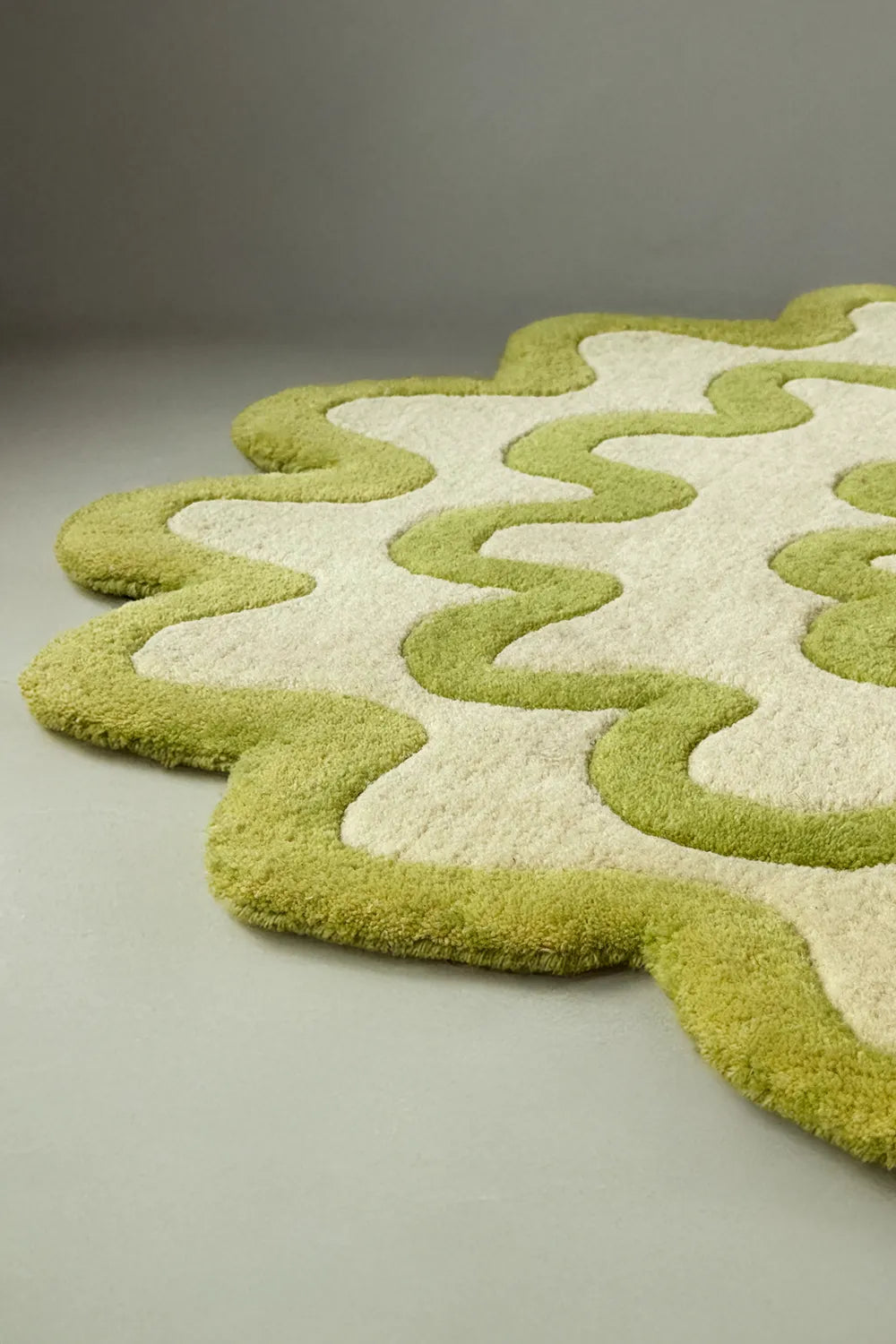Side angle of a lime green and ivory scalloped wool rug, irregular coastal-inspired design lifestyle