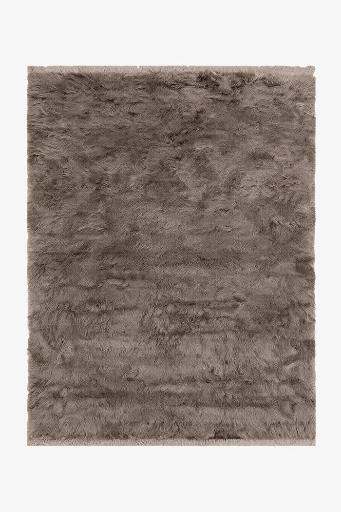 A rectangular shaggy area rug in a taupe-gray color, shown flat against a plain white background.