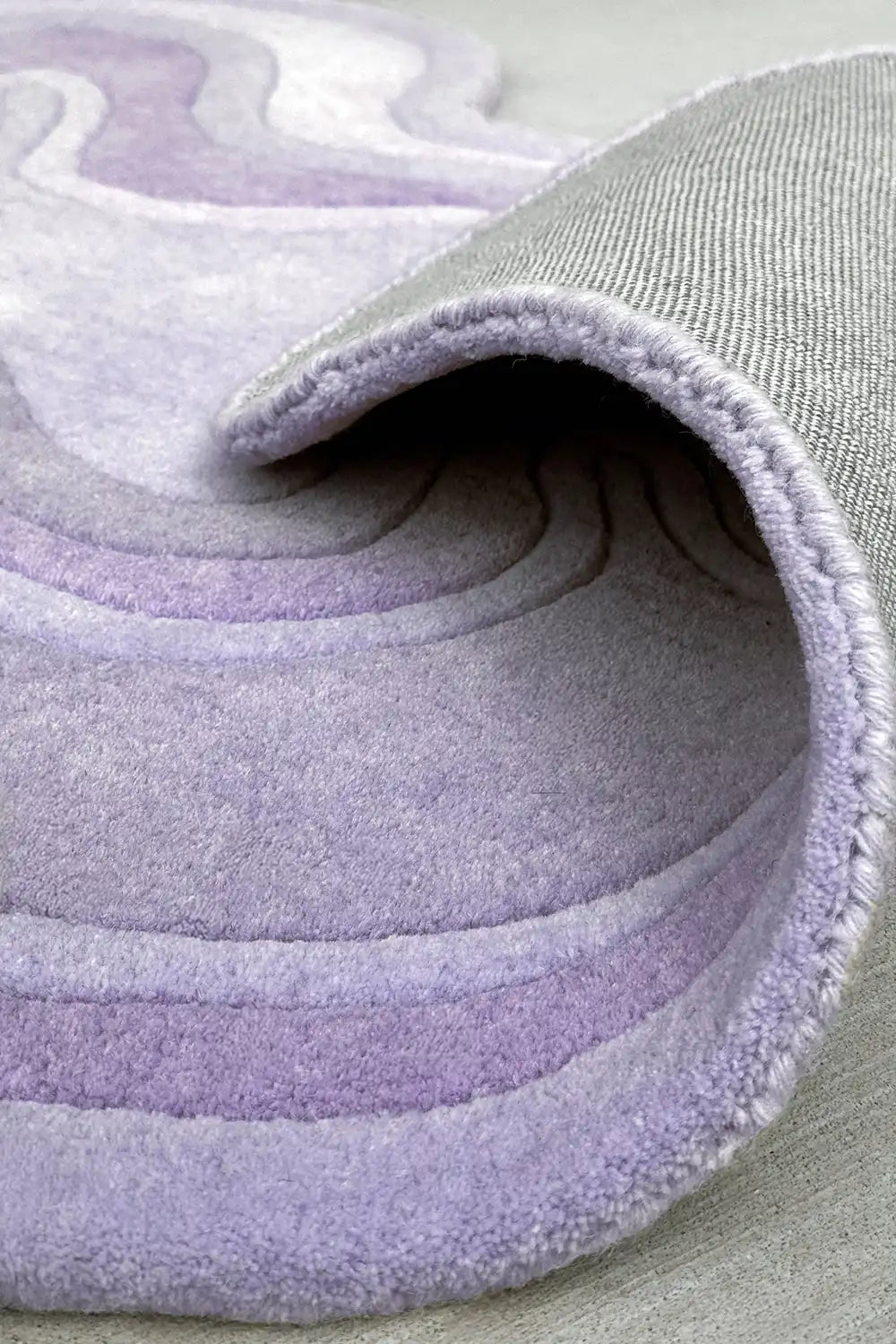 Tufted purple wool rug with ripple-like sculpted texture and soft edge detailing
