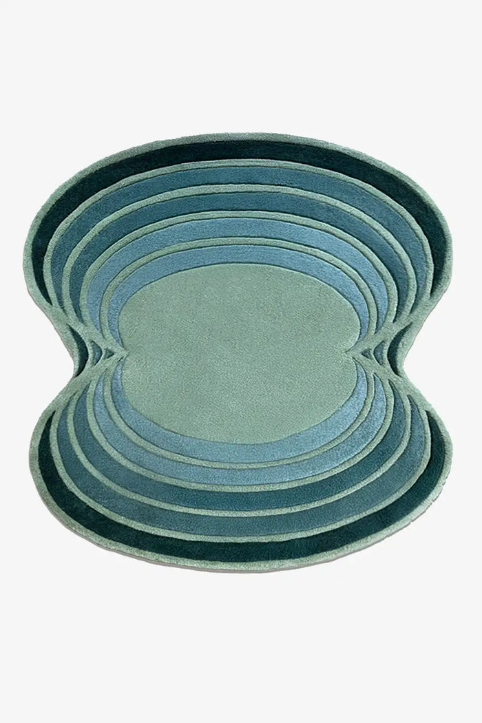 Round irregular shaped green and teal wool rug with sculptural layered edge