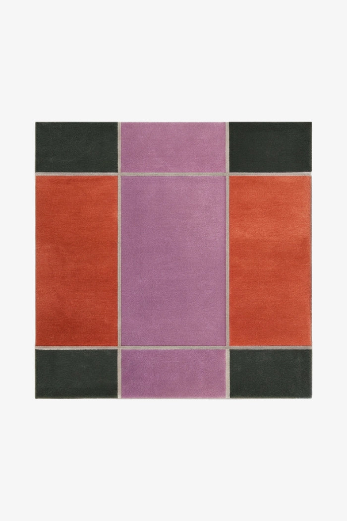 square rug with a geometric pattern of color blocks in orange, purple, and green on a white background