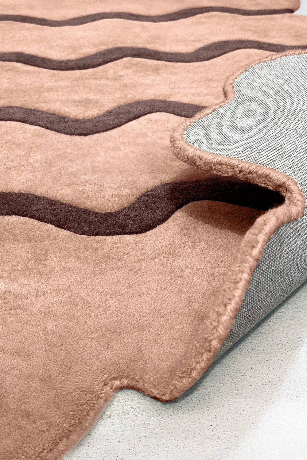 Folded edge of tan and brown hand-tufted ripple wool rug, boutique modern rug