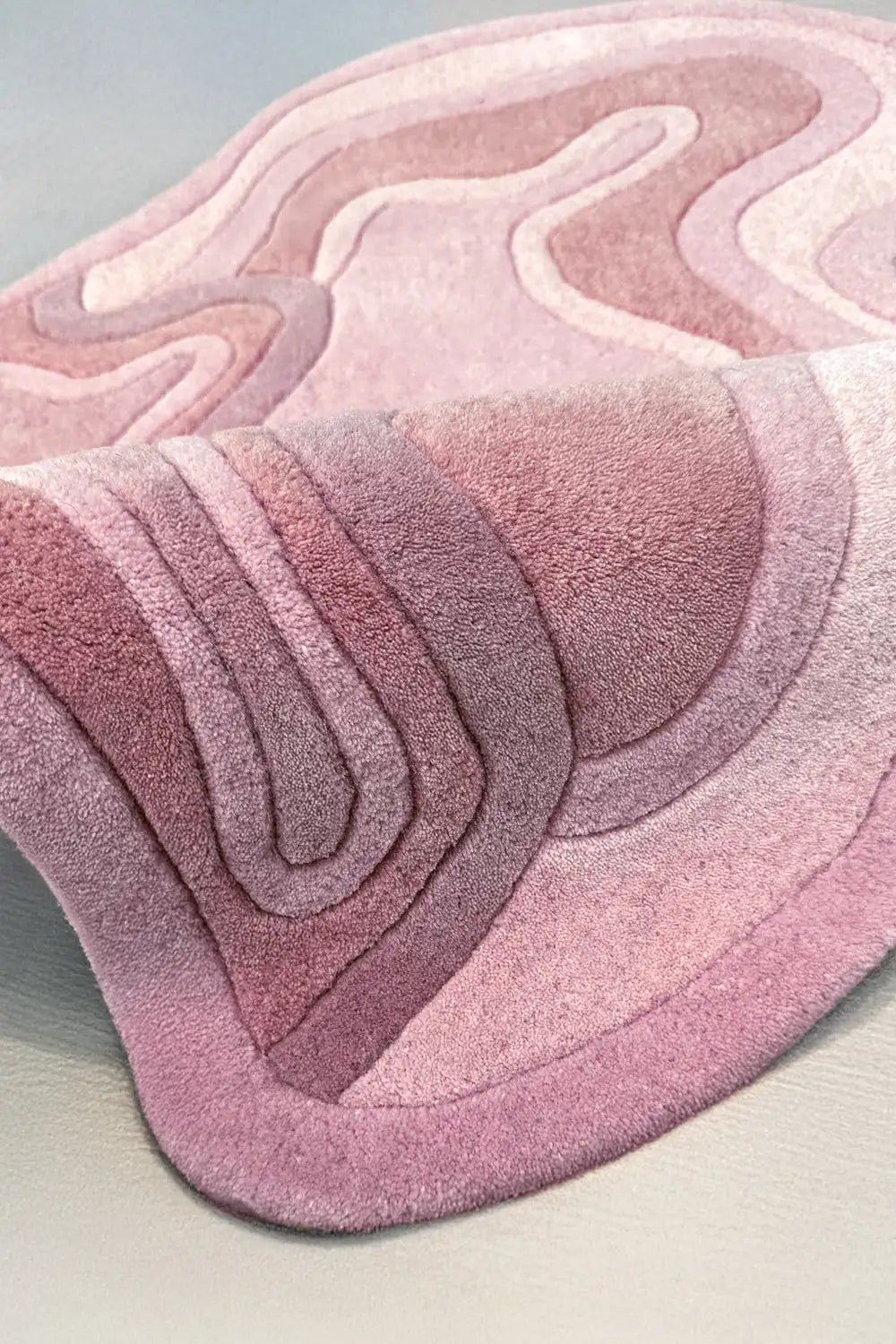 Light pink wool rug with sculpted irregular waves, soft texture and abstract form rose