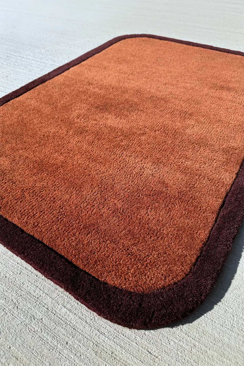 Close-up of thick plush 5x8 brown wool rug with sculptural rounded edge design