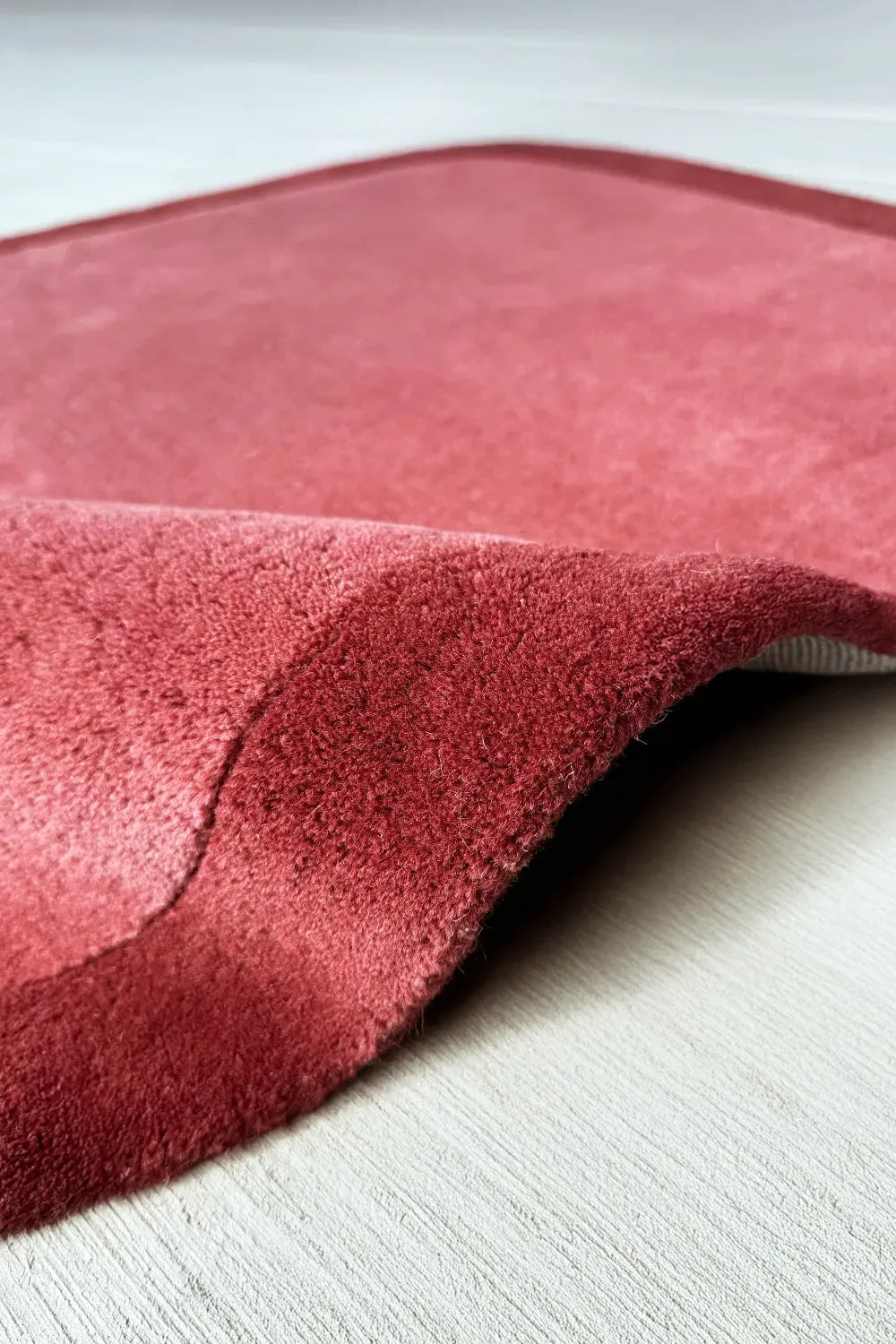 Close up of plush wool texture of a  burnt orange and burgundy unique square shaped area rug