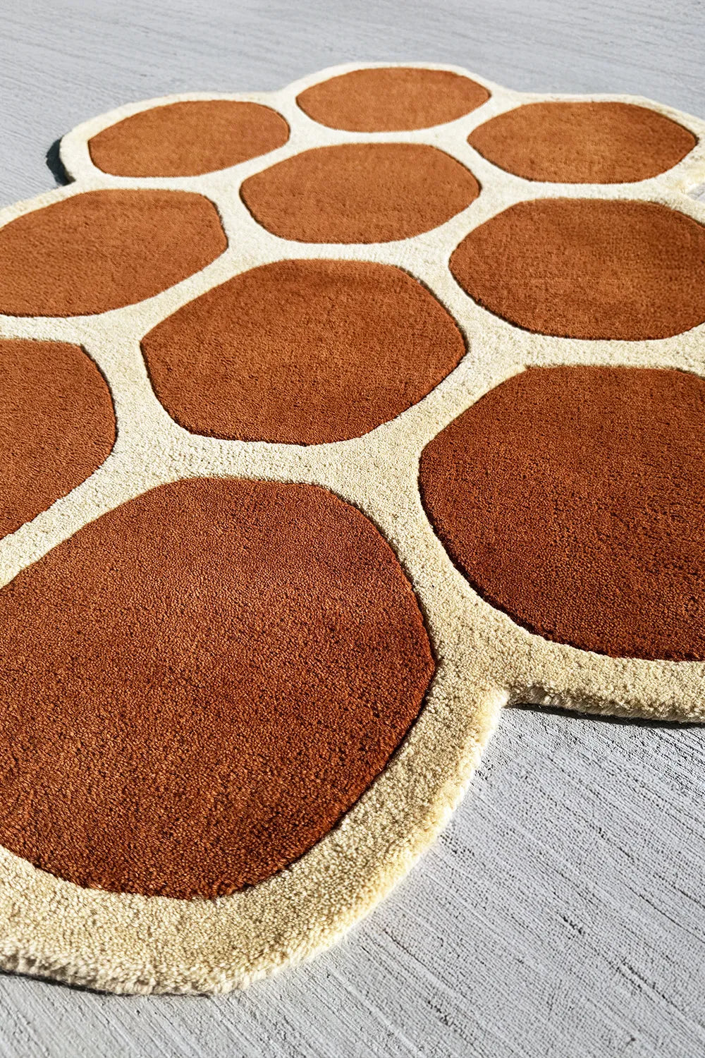 Modern irregular shaped area rug in warm earthy tones with a brown mid century inspired geometric pattern