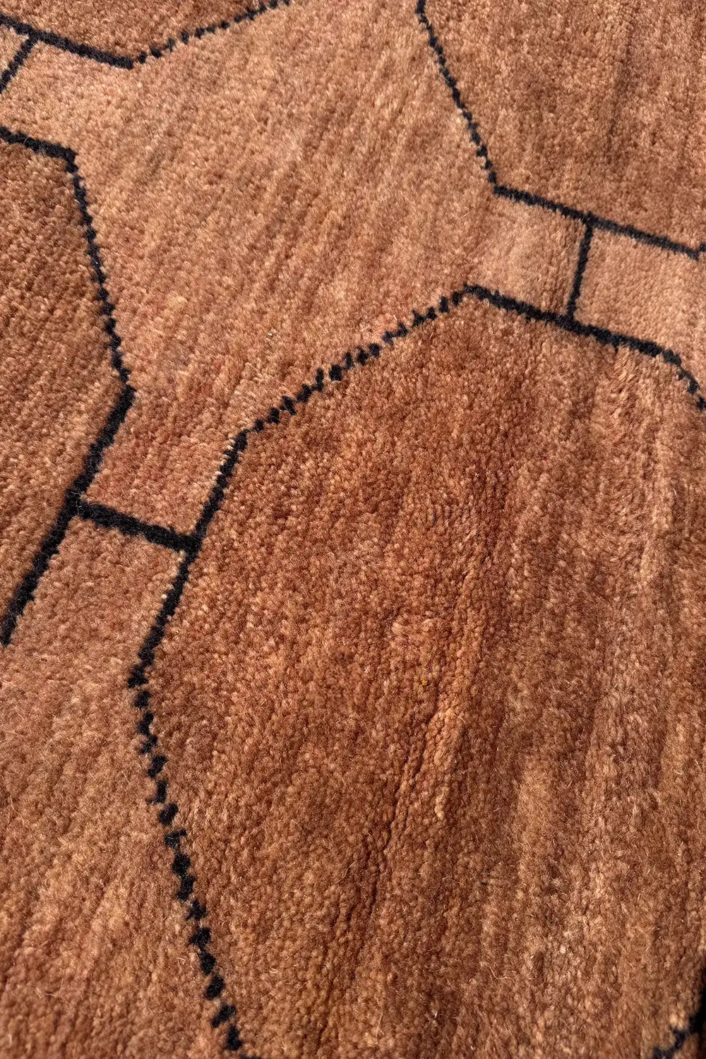 Close-up of brown octagonal pattern with black outlines on a geometric hand-knotted wool rug