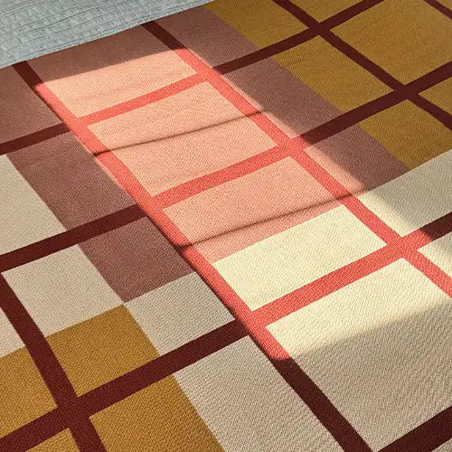 Neutral tan and rust knit blanket with soft organic pattern, shown draped on a bed—great for modern, earth-toned home styling