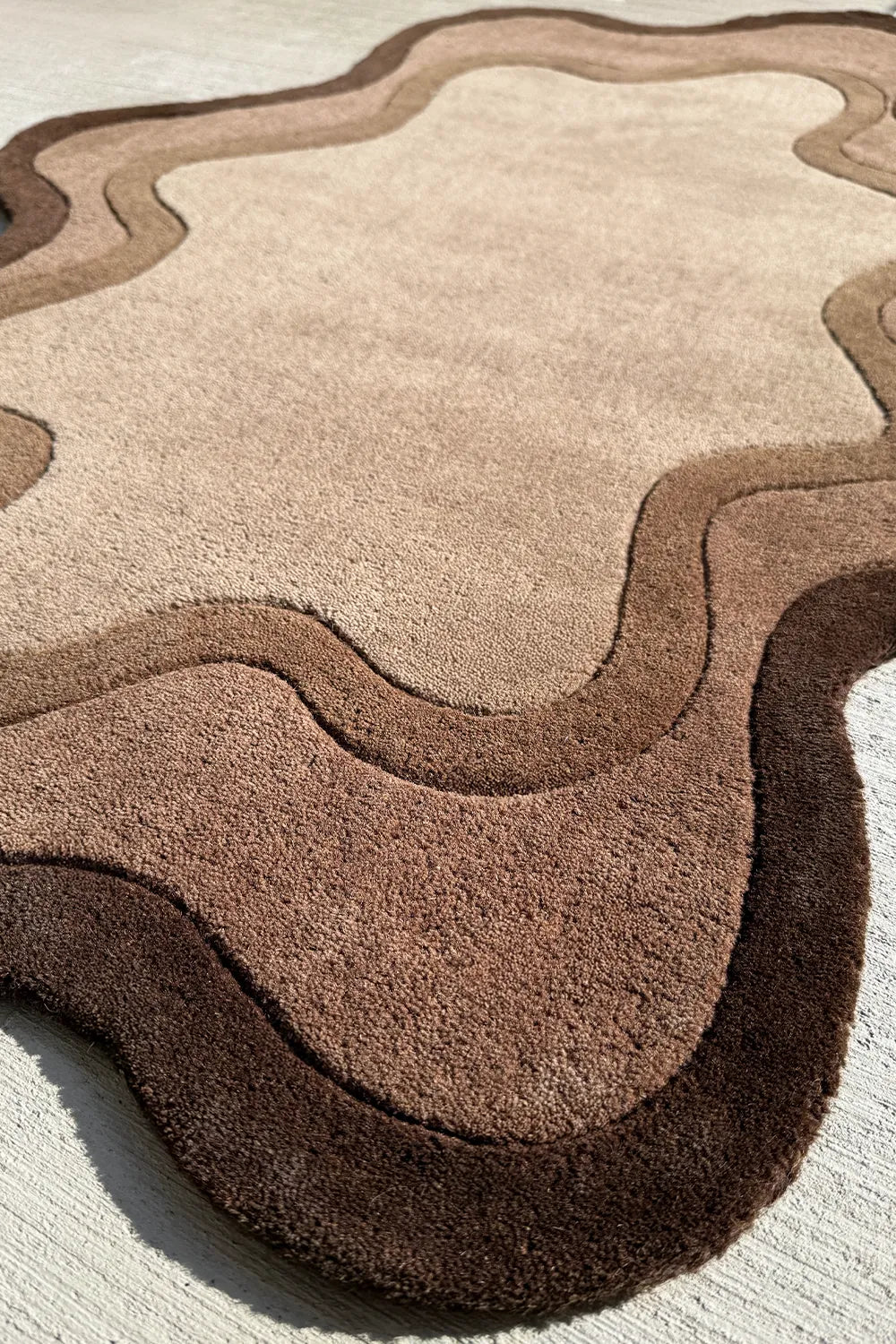 Dark brown custom rug with wavy edges, an asymmetrical boutique rug for earthy and minimalist spaces