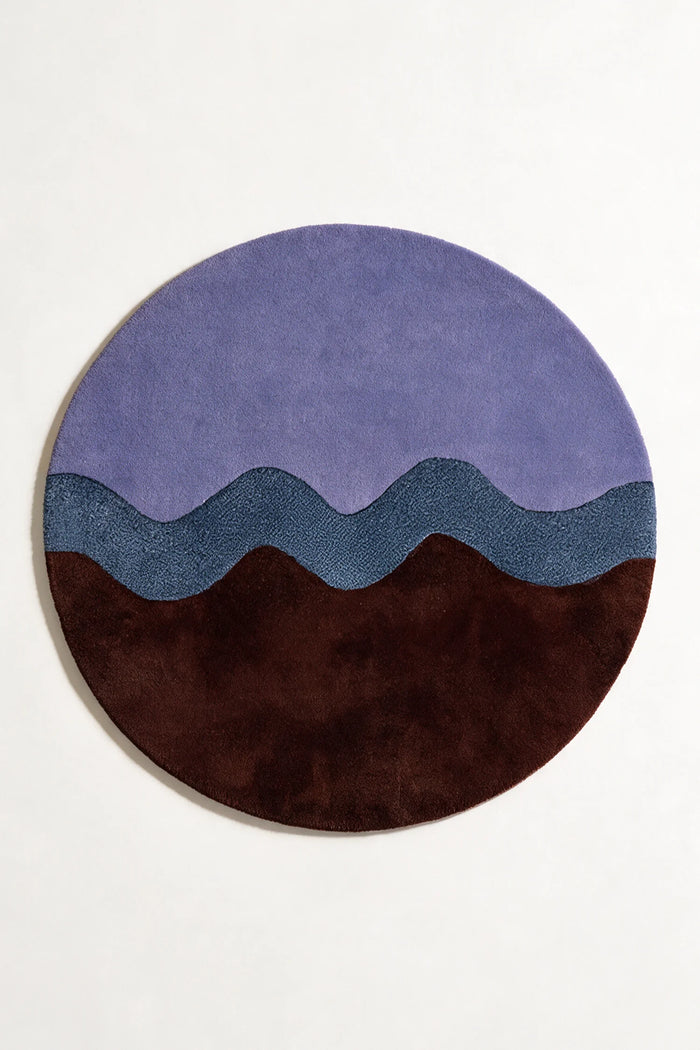 Round modern wool rug in 8x8 size with flowing wavy stripe design in purple, navy, and dark brown