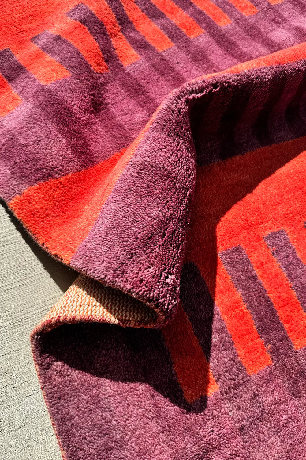 Deep red area rug with contrasting woven lines in a modern geometric pattern