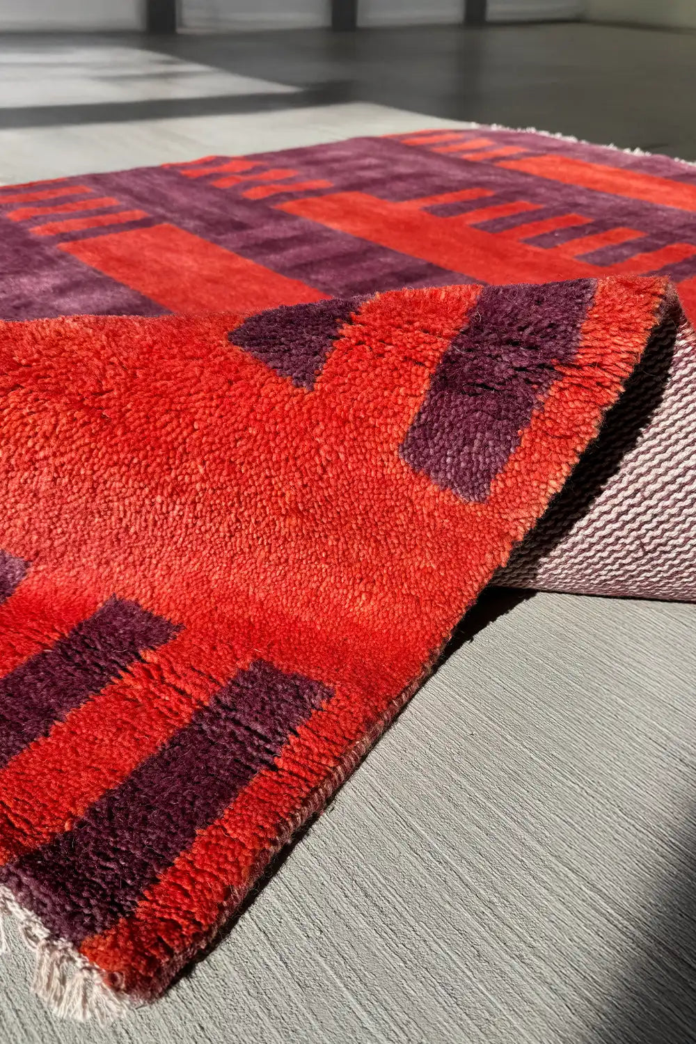Hand-knotted wool rug in deep purple and burnt orange hues