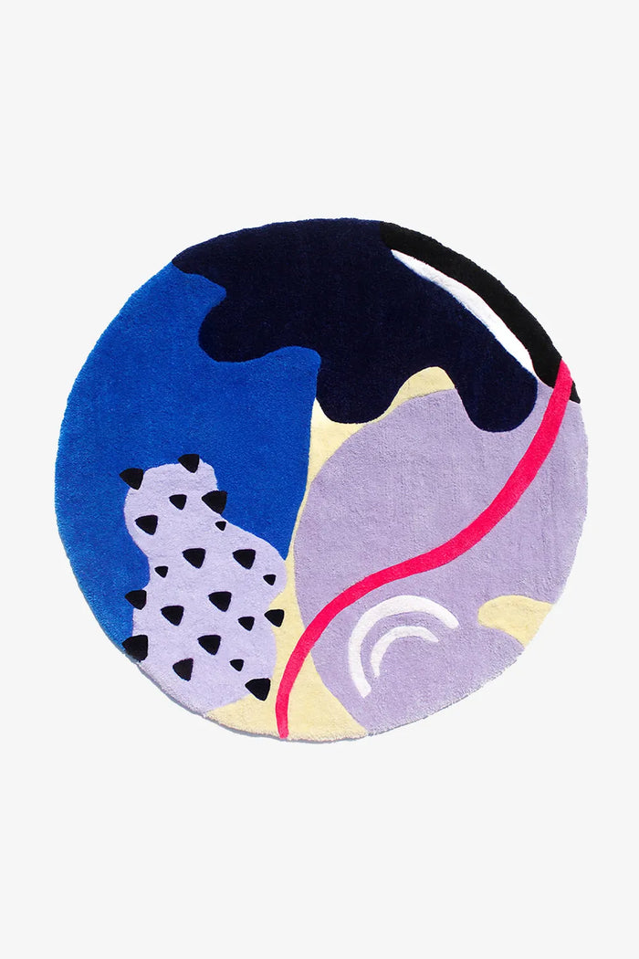 Round colorful abstract wool rug with bold shapes in blue, purple, red, and black