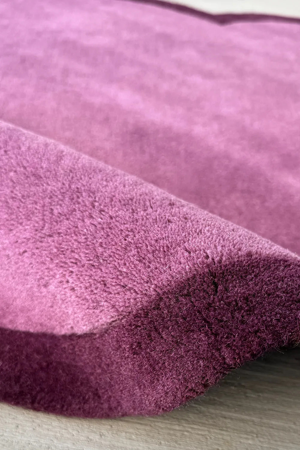 Detailed view of plush wool texture on purple scalloped rug, a luxury designer rug with mid century modern style