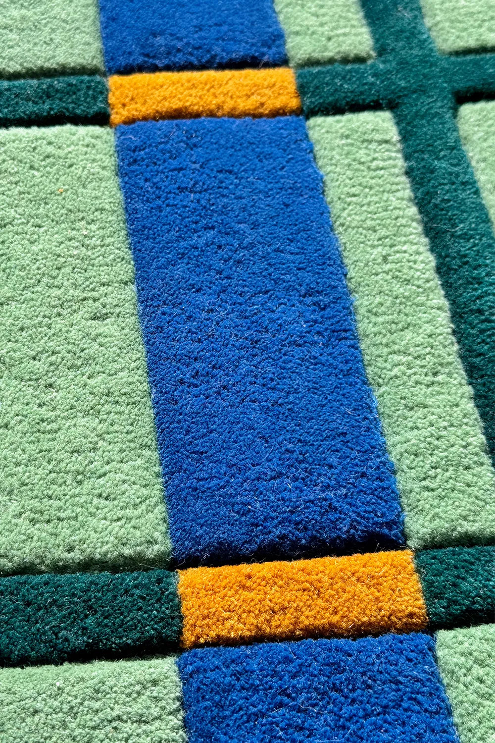 Vintage inspired plaid wool rug with cobalt blue and green blocks, deep tufted pile, and grid symmetry