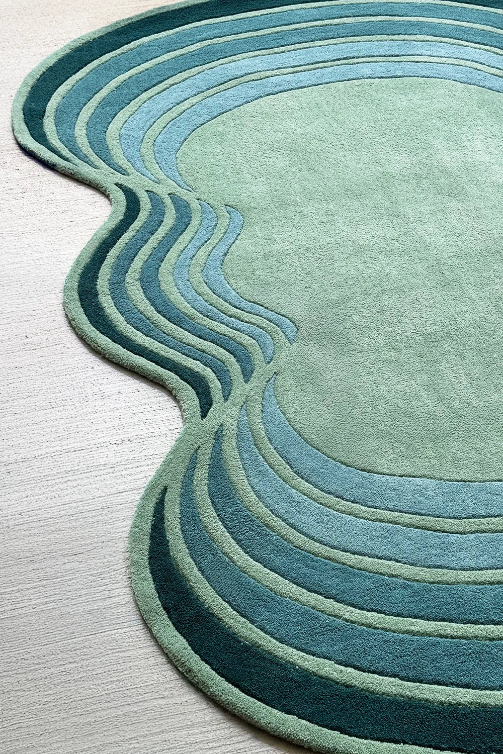 Large irregular shaped green area rug with teal and blue stripes layers, perfect for modern luxury interiors