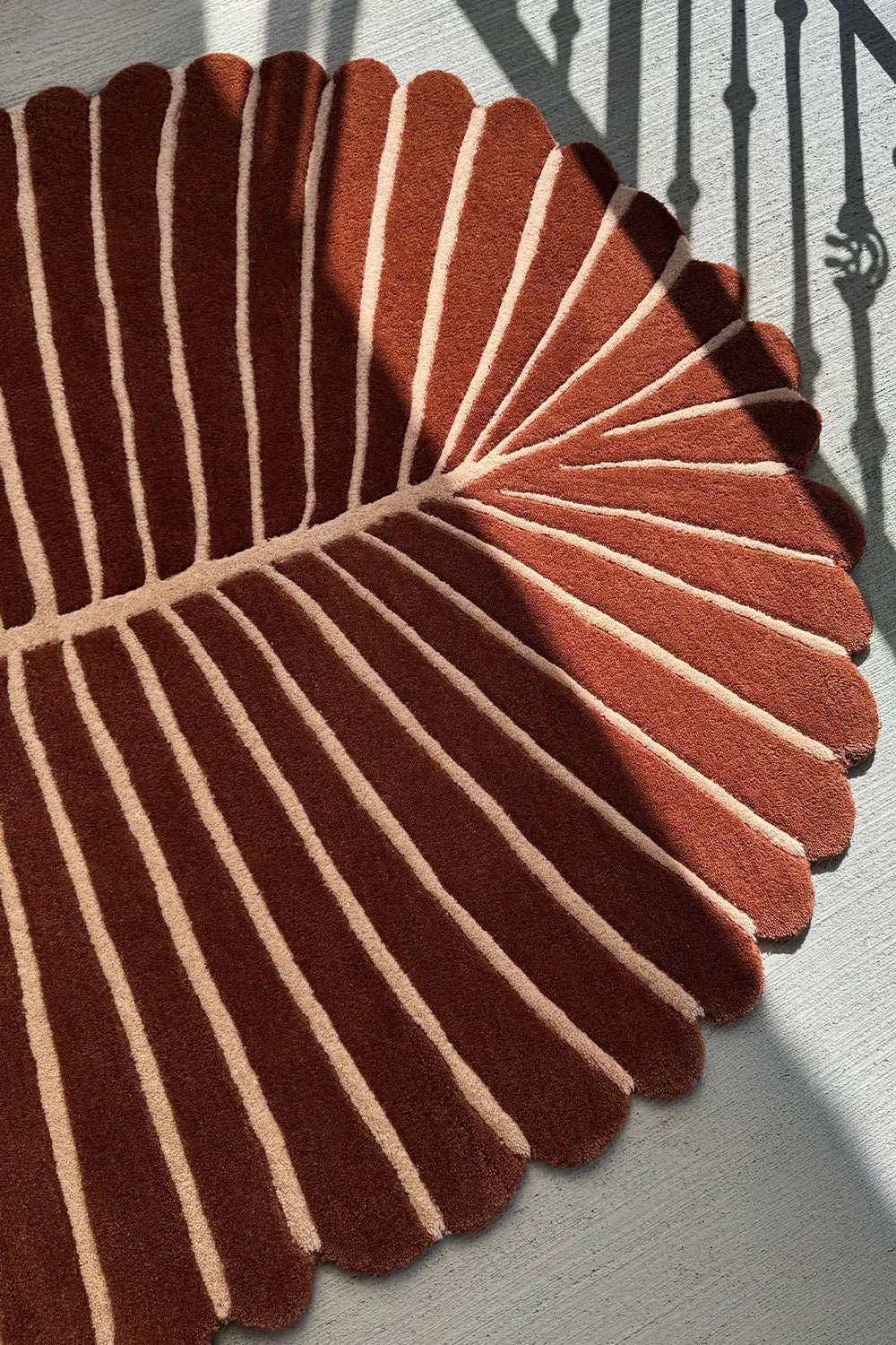 Tropical oval area rug in rich terracotta and cream stripes, with scalloped edges for beach homes or modern interiors
