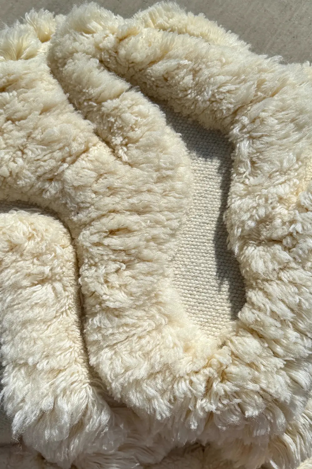 close up of fluffy shag texture of a creamy white irregular shaped wool modern rug