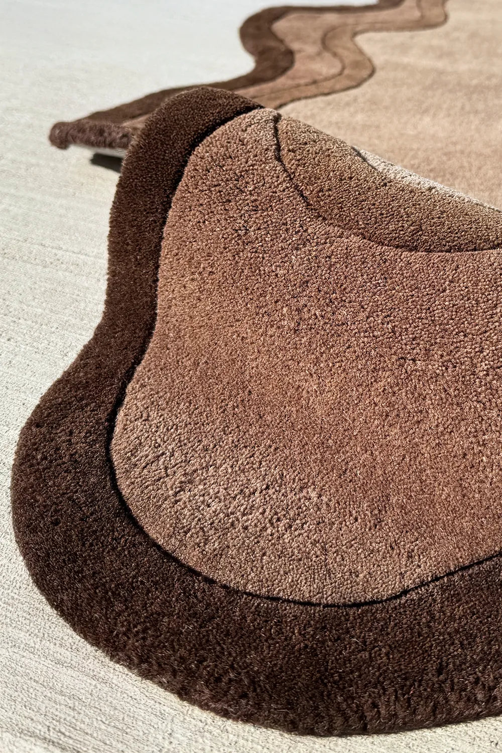 Plush texture of a modern brown wool rug with dark scalloped border for Japandi or boho interiors