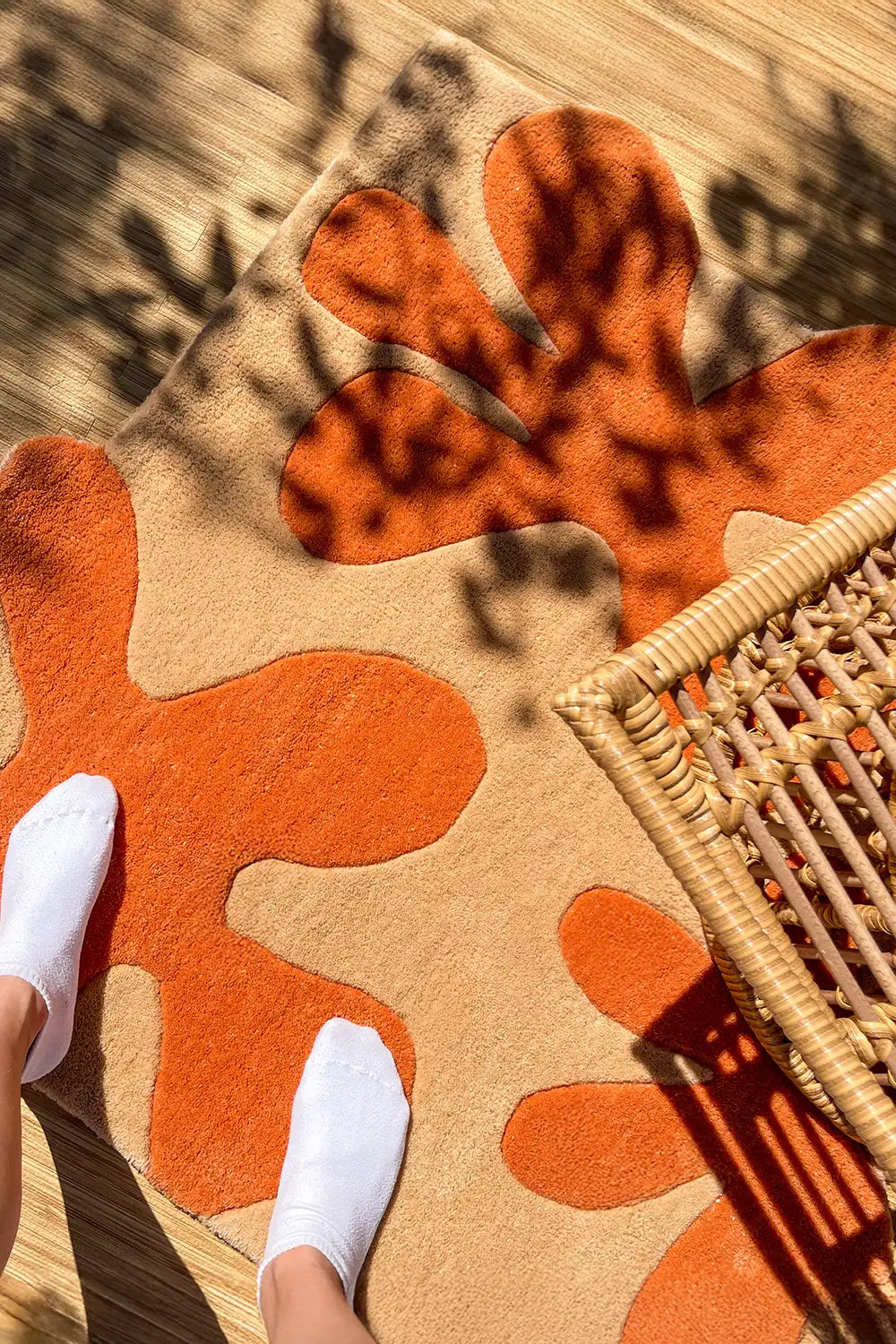 Orange floral abstract square rug catching warm sunlight through leaves lifestyle