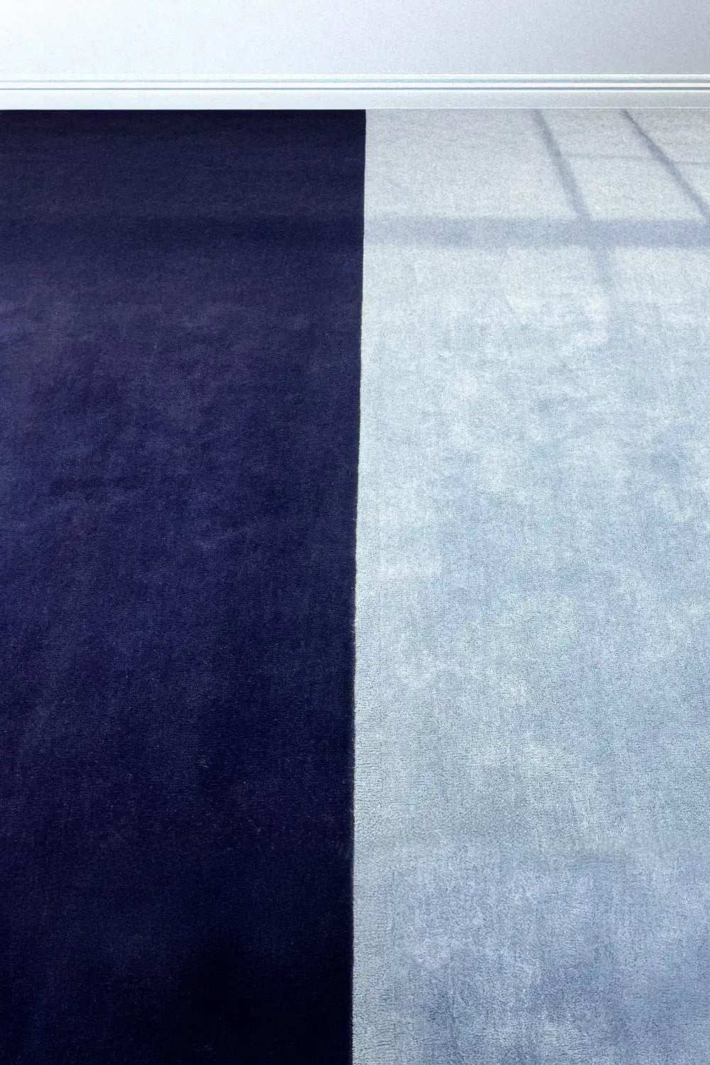 Styled photo of blue and navy block wool area rug showing soft neutral color blocking, ideal for modern coastal or minimal interiors indigo