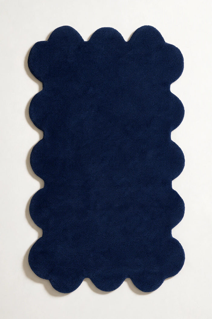 Modern navy blue scalloped rug with soft wool pile and bold sculpted edges, ideal for moody interiors