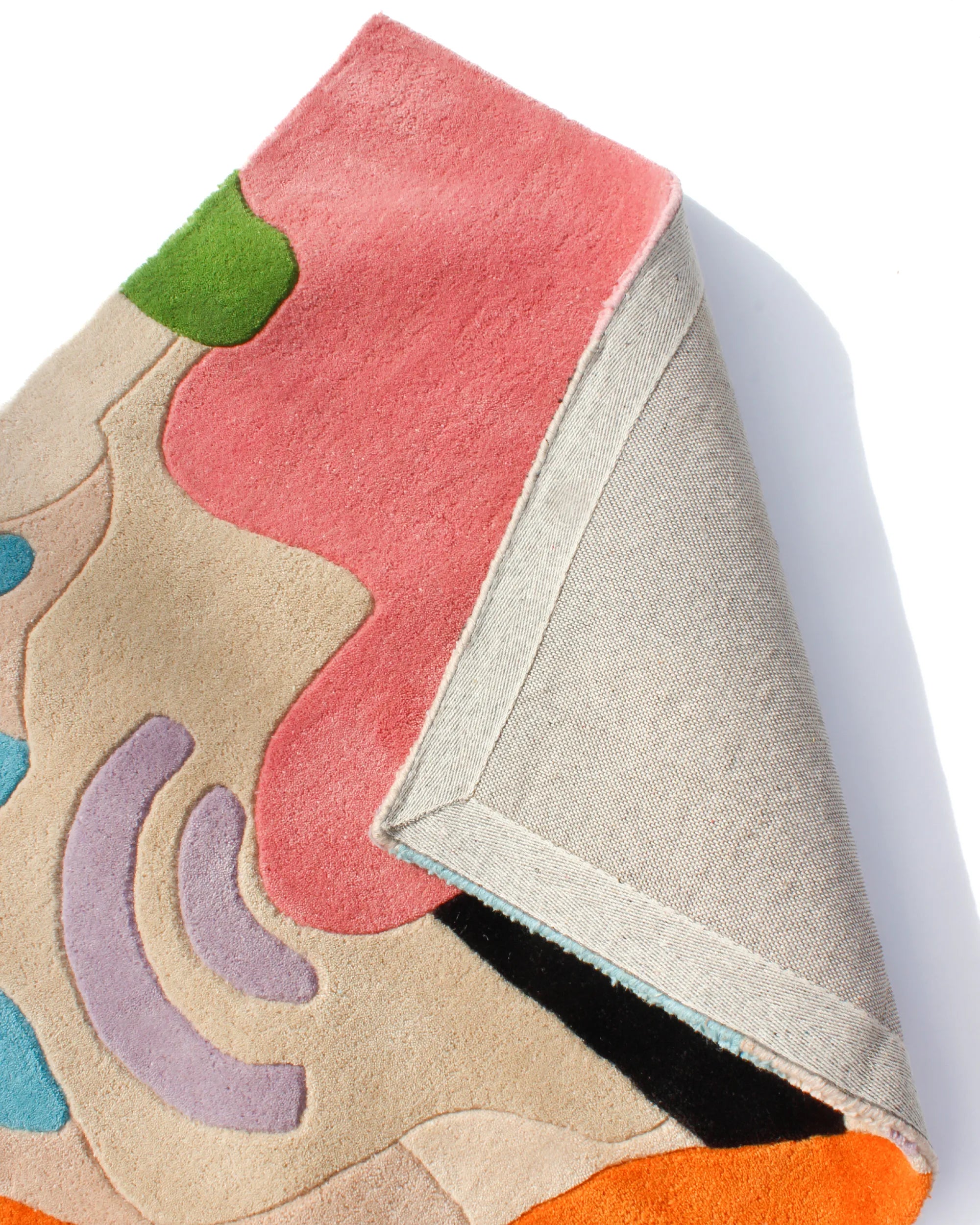 Detail of colorful tropical wool rug with overlapping botanical and wave motifs