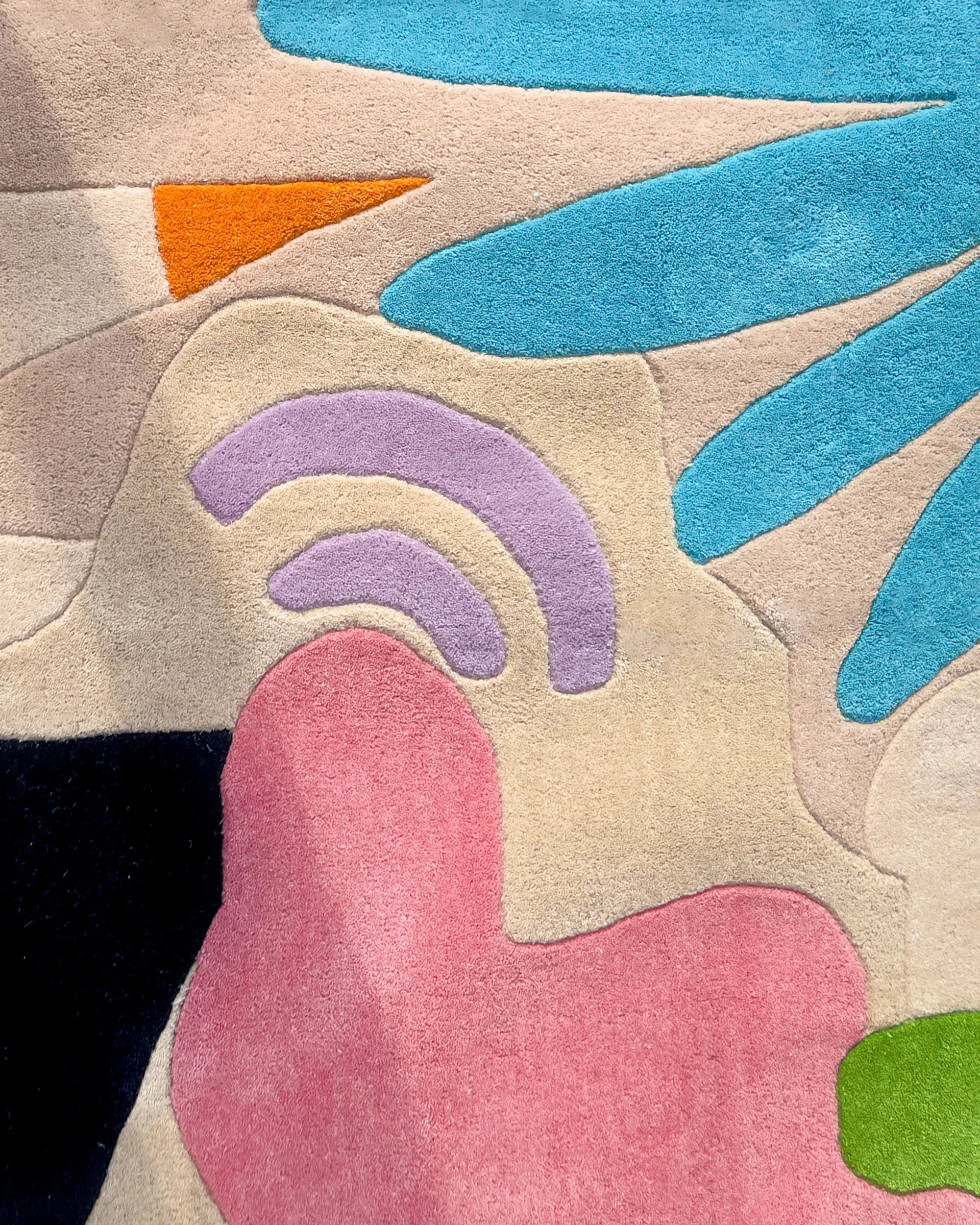 Close-up of tropical abstract area rug showing pink, lavender, orange, and blue tufted shapes
