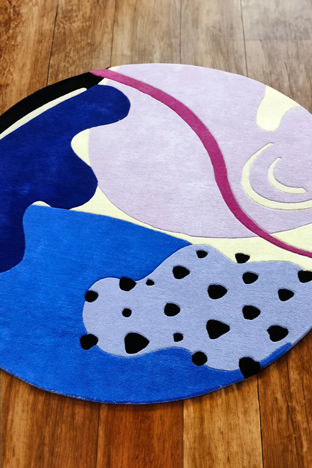 Circular funky area rug with modern abstract design on hardwood floor lifestyle