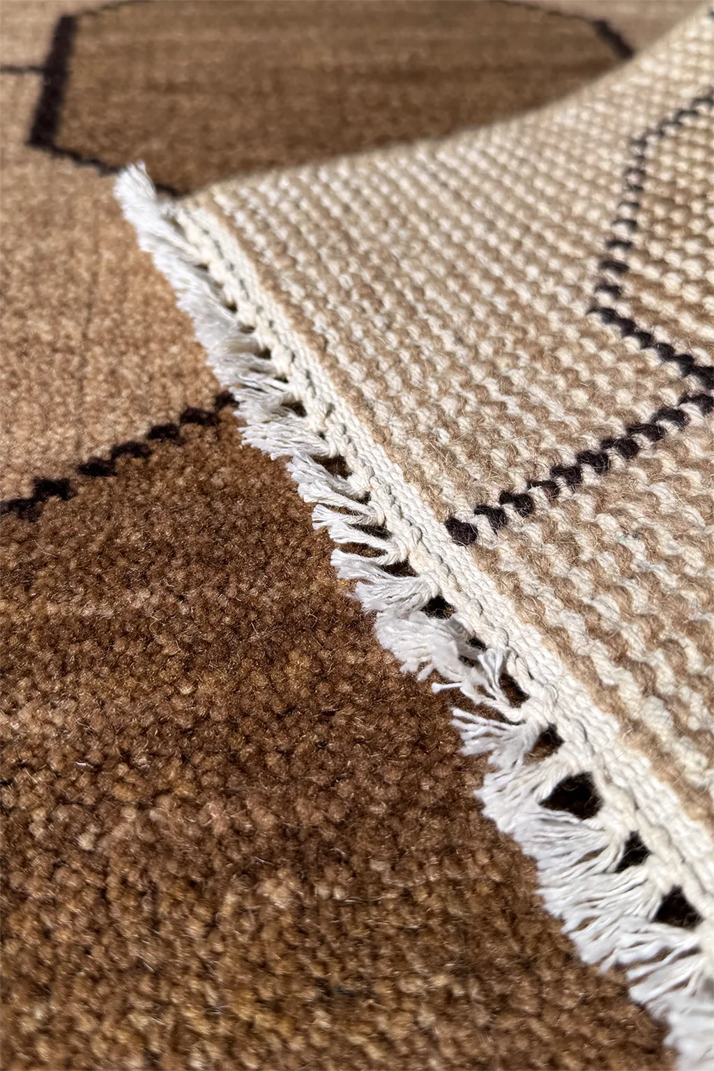 Close-up of a textured neutra; runner rug with a white border and geometric pattern.