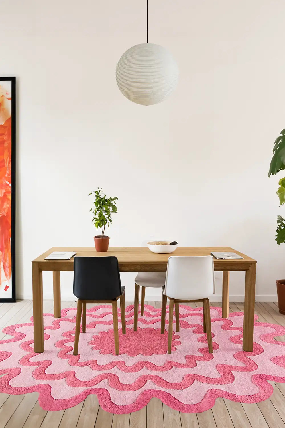 Pink and red colorful wool rug under minimalist wood dining table in bright dining room.