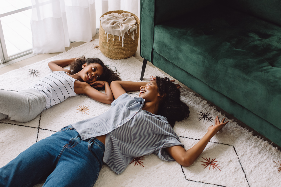 mother and daughter laying on a soft wool rug in modern living room