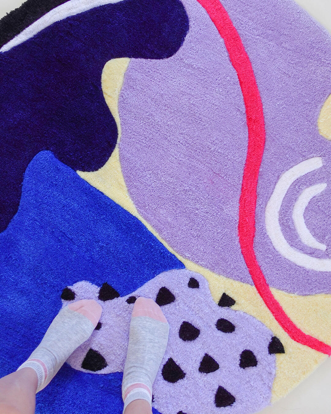Detail of vibrant round wool rug showing lavender, cream, and hot pink accents