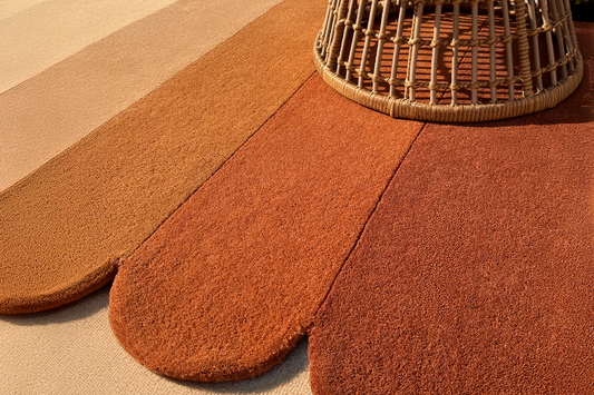modern gold and burnt orange scalloped wool rug in a boho room under rattan chair