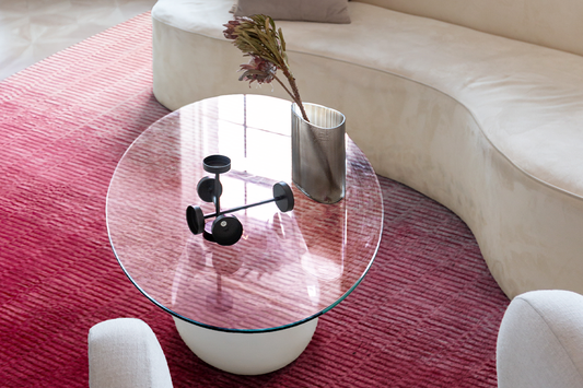 Modern living room featuring the Pink Ombre tufted wool rug by Jubi, styled with a curved white sofa and round glass coffee table.