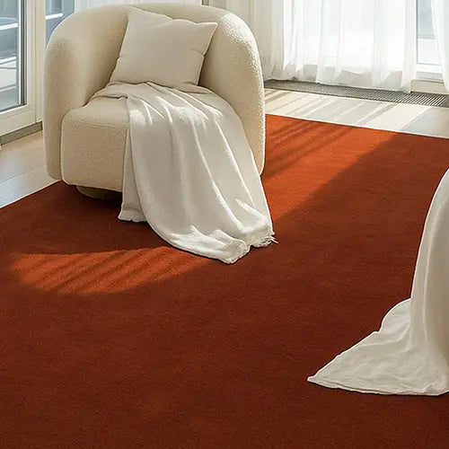 large burnt orange wool area rug in a modern bedroom with white chair