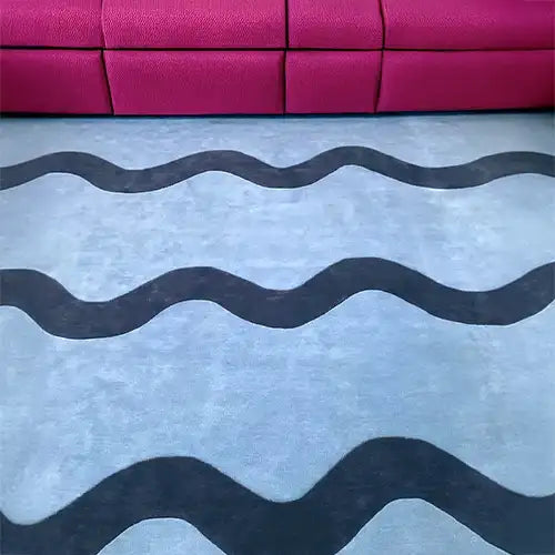 Modern 8x10 light blue scalloped wool rug with navy wavy stripes in a modern living room with hot pink couch