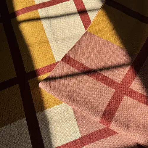 Neutral knit throw blanket in tones of cream rust and mustard in a sunny room