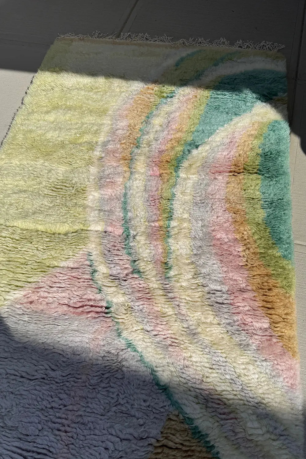 Colorful abstract shag wool rug in sunlight, pastel tones in sculpted ripple texture