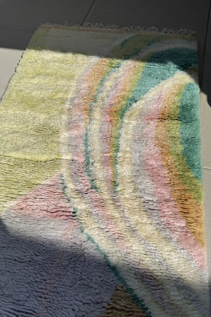 Colorful abstract shag wool rug in sunlight, pastel tones in sculpted ripple texture